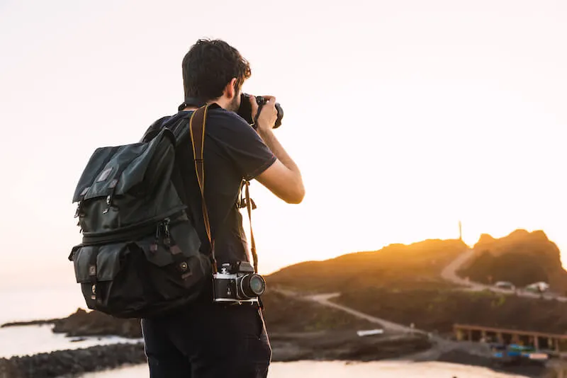 男人和古董相机和旅行背包在日落时分